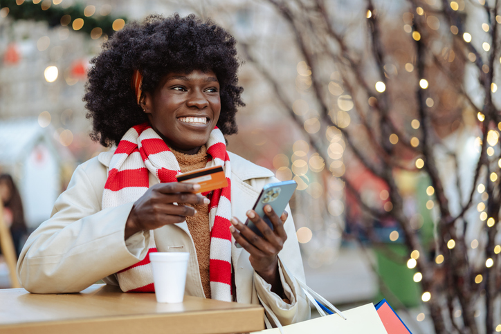 Woman enjoying holiday shopping with coffee and smartphone