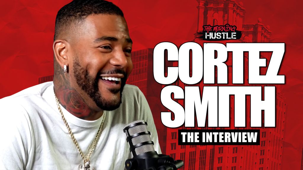 A smiling man with a beard wearing a white shirt and jewelry, the text "Cortez Smith The Interview" and "The Morning Hustle" visible in the background.