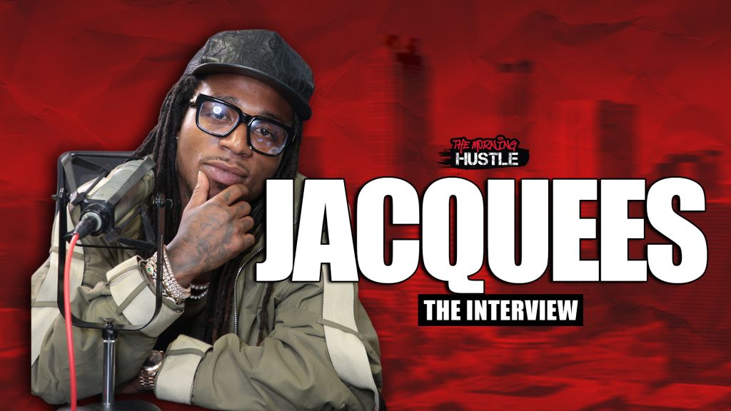 A man wearing glasses, a hat, and a jacket sitting in front of a microphone, with the text "The Morning Hustle" and "Jacquees The Interview" visible.